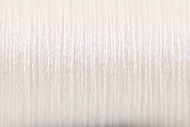 May include: Close-up of white thread with a subtle sheen.