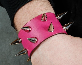 Pulsera tipo brazalete de cuero rosa hecha a mano con pinchos plateados.