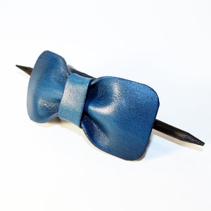 May include: A blue leather bow tie hair clip with a black wooden stick.