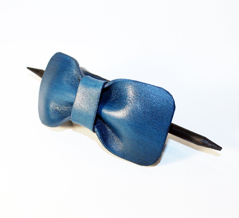 May include: A blue leather bow tie hair clip with a black wooden stick.