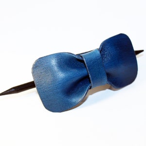 May include: A blue leather bow tie hair clip with a black wooden stick.