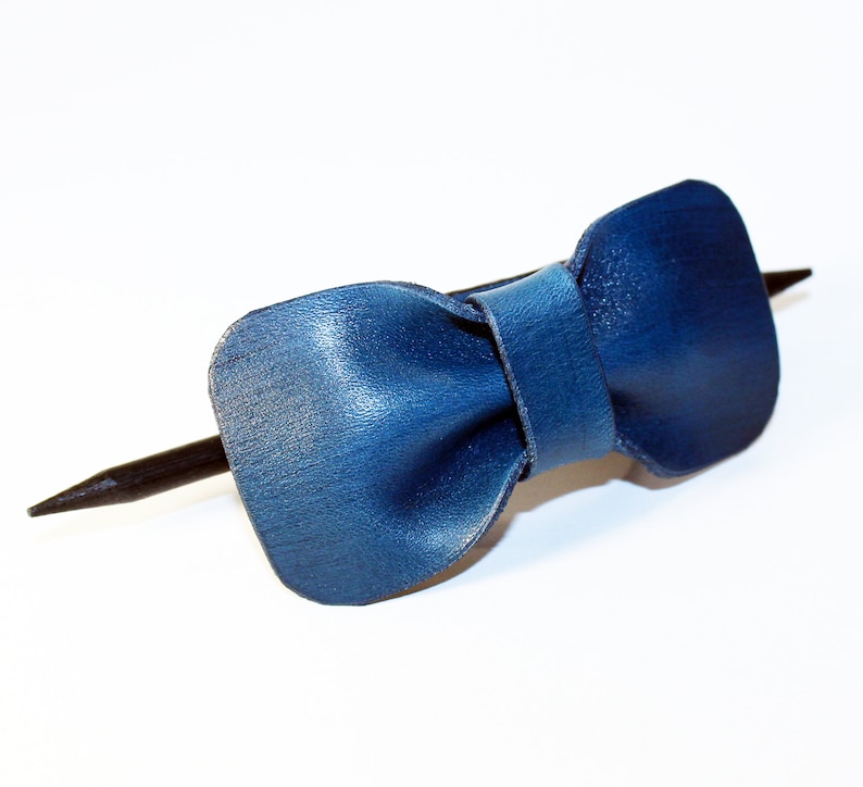 May include: A blue leather bow tie hair clip with a black wooden stick.