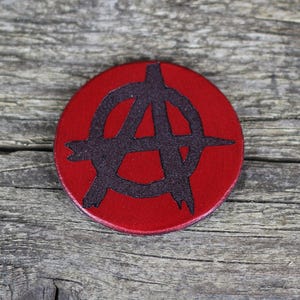 Peut inclure: Un cercle en cuir rouge avec un symbole d'anarchie noir.