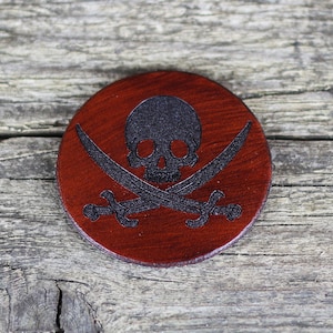 May include: A round, red leather coaster with a black skull and crossbones design.