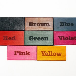 May include: Nine small leather squares with the words "Black", "Brown", "Blue", "Red", "Green", "Violet", "Pink", "Yellow" written in black lettering.