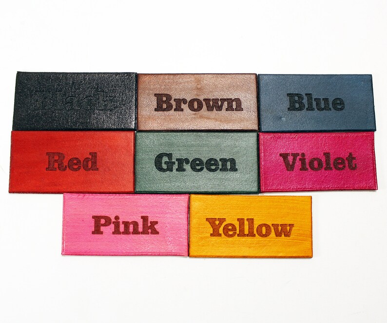 May include: Nine small leather squares with the words "Black", "Brown", "Blue", "Red", "Green", "Violet", "Pink", "Yellow" written in black lettering.