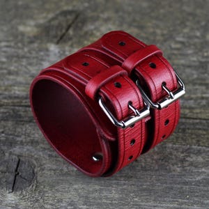 May include: A red leather double buckle cuff bracelet with silver buckles.