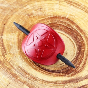 May include: A red leather hair stick with a five-pointed star design. The stick is made of wood and has a black finish.