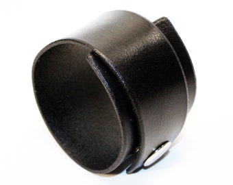 May include: A black leather cuff bracelet with a silver snap closure.