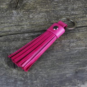 Peut inclure: Un porte-clés en cuir rose avec un anneau de clé argenté.