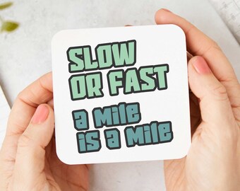 May include: White coaster with green and blue text that reads "Slow or Fast a Mile is a Mile".