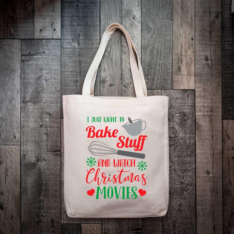 May include: Cream-colored tote bag with the text "I just want to Bake Stuff and watch Christmas Movies" in red and green. The design includes a whisk, mixing bowl, snowflakes, and hearts. The bag has two handles.