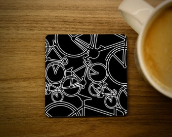 May include: Black coaster with a white outline of bicycles repeating in a pattern.