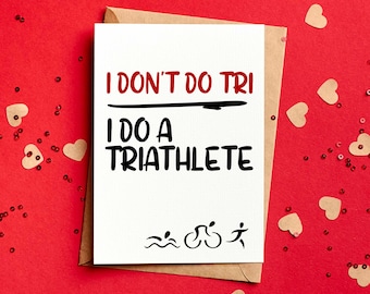 May include: A white card with the text "I don't do tri I do a triathlete" in black. The card is decorated with a black line, a black swimming icon, a black bicycle icon, and a black running icon. The card is on a brown envelope with a red background.