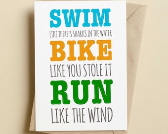 May include: A white greeting card with colorful text that reads: SWIM LIKE THERE'S SHARKS IN THE WATER, BIKE LIKE YOU STOLE IT, RUN LIKE THE WIND. The words SWIM, BIKE, and RUN are in blue, orange, and green, while the other text is in gray.