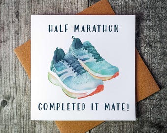May include: A white card with the text "HALF MARATHON COMPLETED IT MATE!" and a watercolour illustration of two blue running shoes.