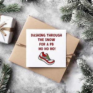 May include: A Christmas-themed greeting card with the text "Dashing Through The Snow For A PB Ho Ho Ho!" and a cartoon running shoe. The card is on a brown envelope, decorated with twine, and surrounded by festive greenery.