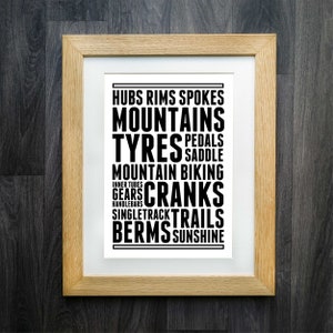 May include: A framed print with black text on a white background. The text reads "Hubs Rims Spokes Mountains Tyres Pedals Saddle Mountain Biking Inner Tubes Gears Cranks SingleTrack Trails Berms Sunshine".