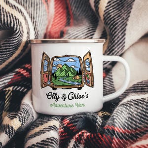 Könnte beinhalten: Weißer Emaille-Campingbecher mit silbernem Rand. Der Becher zeigt eine farbenfrohe Illustration eines Vans mit geöffneten Türen, die eine Berglandschaft offenbaren. Der Text auf dem Becher lautet "Olly & Chloe's Adventure Van."
