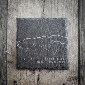 Może przedstawiać: Czarny podkładka ze łupka z białym obrysem pasma górskiego i tekstem "I climbed Scafell Pike 978m | 19/08/2023".