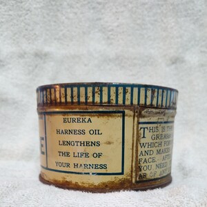 May include: A vintage tin can of Eureka Harness Oil. The label reads "Eureka Harness Oil Lengthens The Life Of Your Harness" and "This is the grease which for and makes face. After you need ab of any".