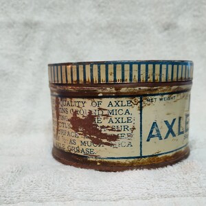 May include: A vintage tin can of axle grease with blue and white striped lid and label that reads "QUALITY OF AXLE GREASE, CONTAINS GROUND MICA, PERFECTLY SMOOTH SURFACE, AS MUCH WEAR AS ANY AXLE GREASE. NET WEIGHT 1 LB. AXLE GREASE".