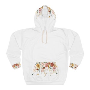 Op de afbeelding: Witte hoodie met een bloemenprint op de capuchon, zak en manchetten. De bloemenprint heeft een verscheidenheid aan kleuren, waaronder rood, roze, geel en groen.