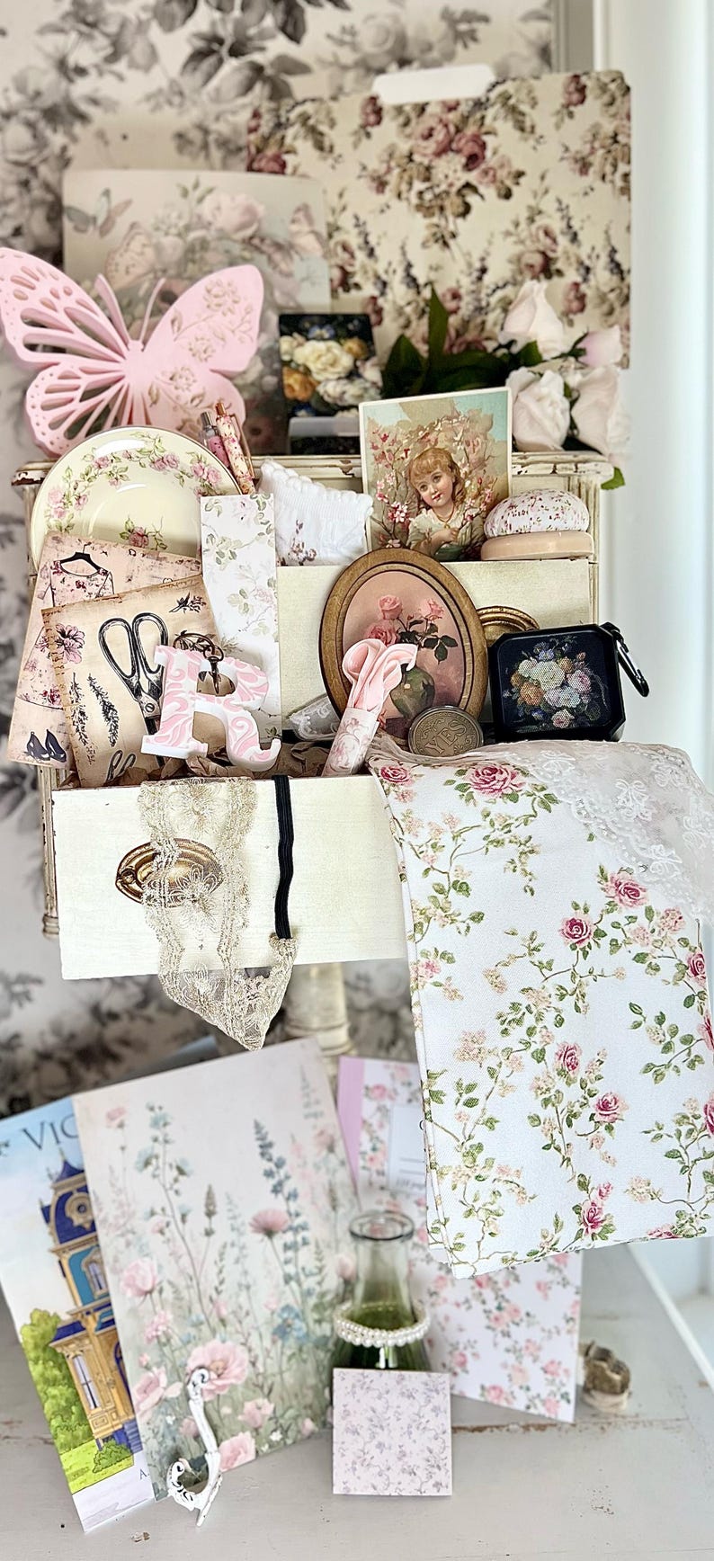 May include: A collection of vintage-style items, including a pink butterfly, floral-patterned plates, fabric, and artwork. The color palette is soft, featuring pinks, creams, and greens, creating a romantic and feminine aesthetic.
