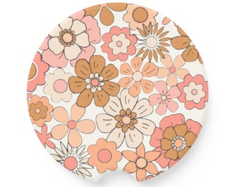 May include: A round coaster with a white background and a floral pattern in shades of pink, brown, and cream. The flowers are stylized and have a retro feel.