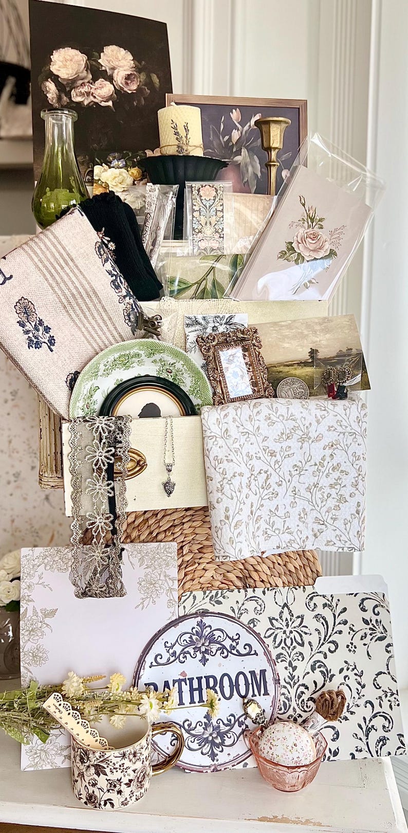 May include: A collection of vintage-style home decor items, including floral prints, a decorative plate, a necklace, and a sign that says "Bathroom". The color palette includes white, beige, green, and gold accents, creating a romantic and elegant aesthetic.