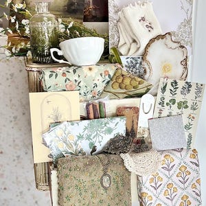 May include: A collection of vintage-style items, including a teacup, floral-patterned fabric, postcards, and a small painting. The items are arranged in a decorative, antique-style storage unit. A sign that says "Pantry" is visible.