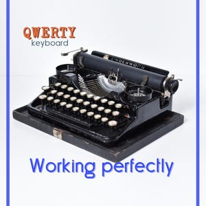 May include: A black Underwood typewriter with a QWERTY keyboard layout and circular keys. The machine features a metal frame, a carriage, and ribbon spools. Text on the image reads QWERTY keyboard and Working perfectly in blue and orange.