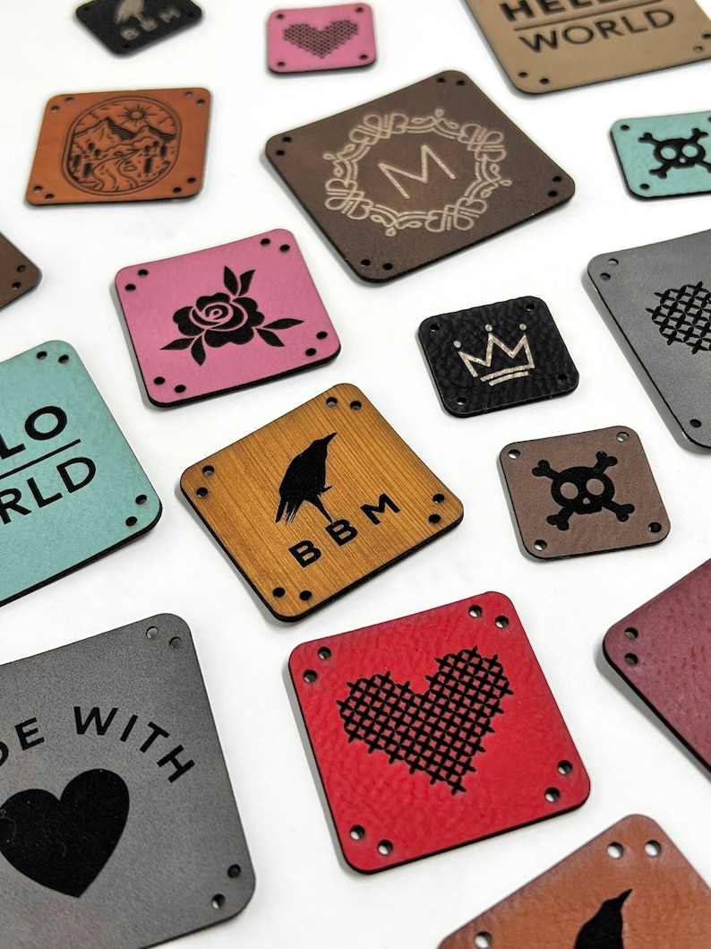 May include: A collection of square and rectangular faux leather tags in various colors including red, pink, brown, gray, and teal. Each tag features pre-punched corner holes and laser-engraved designs such as hearts, skulls, crowns, and text.
