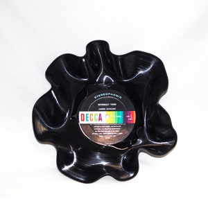 May include: A black vinyl record has been melted and reshaped into a bowl. The center label is still visible and reads "Decca" and "Informal Tours" by Carmen Cavallaro. The label is colorful with a rainbow stripe.