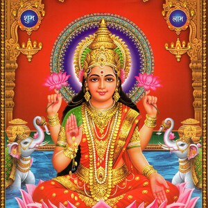 Puede incluir: Una representación de Lakshmi, la diosa hindú de la riqueza y la prosperidad, sentada sobre una flor de loto rosa. Está adornada con joyas de oro y sostiene una flor de loto en cada mano. La imagen incluye las palabras "Shubh" y "Lam" en hindi.