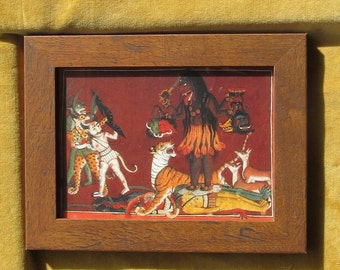 Puede incluir: Pintura enmarcada que representa una figura de piel oscura con múltiples brazos, de pie sobre un tigre y otras figuras. La obra de arte presenta colores vibrantes, incluyendo rojo, naranja y verde, sobre un fondo rojo. El marco es de madera marrón.
