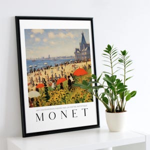 Puede incluir: Una impresión enmarcada de una pintura de Claude Monet que representa una escena de playa con personas y sombrillas rojas. La pintura se titula "Art Contemporain Inspire Par Un Maitre Artistique" y el nombre del artista "MONET" está impreso debajo de la pintura.