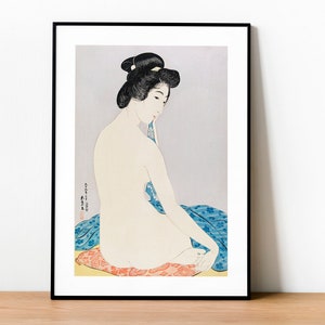 Puede incluir: Una impresión japonesa vintage en madera que representa a una mujer con un kimono estampado en azul y rojo sentada en un cojín. La mujer está desnuda y de espaldas al espectador. La impresión está en un marco negro.