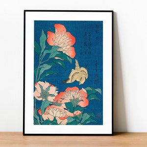 Puede incluir: Una estampa japonesa en madera que representa un pájaro volando cerca de peonías rosas y blancas sobre un fondo azul. La estampa incluye texto japonés.