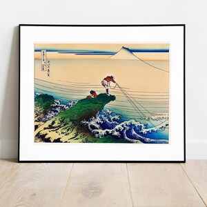 Puede incluir: Una estampa en madera que representa una escena de pescadores tirando de una red con el monte Fuji de fondo. La estampa está en un estilo japonés tradicional con colores vibrantes y detalles intrincados.