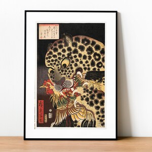 Puede incluir: Una estampa japonesa en madera que representa un leopardo con manchas negras y amarillas atacando a un gallo. La boca del leopardo está abierta, mostrando dientes afilados, y sus ojos están muy abiertos. El gallo es rojo, amarillo y blanco con una cola larga y fluida. El fondo es negro.