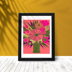 Puede incluir: Una impresión artística enmarcada que presenta un ramo floral estilizado. La obra de arte muestra una vibrante disposición de flores rosas, verdes y moradas sobre un fondo coral. El ramo está en un jarrón verde, todo dentro de un marco negro.