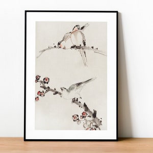Puede incluir: Una pintura enmarcada en tinta negra y blanca de dos pájaros posados en una rama con flores rojas. Los pájaros están en un estilo japonés tradicional.