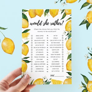 May include: A lemon-themed baby shower game card with the text "would she rather?" and a list of 16 questions with two choices each. The card is decorated with watercolor illustrations of lemons and flowers.