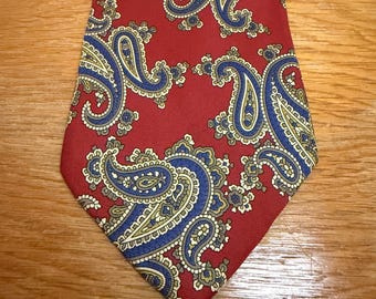 May include: A red necktie with a repeating paisley pattern in blue, yellow, and white. The tie is made of a smooth fabric and is suitable for formal or business attire.