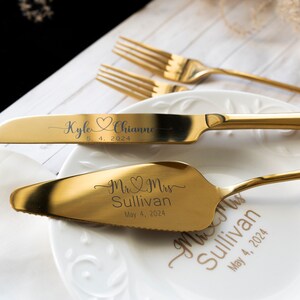 May include: A gold-toned cake knife and server set with custom engraving. The knife features the names Kyle and Chianne with a heart icon and the date 5. 4. 2024. The server is engraved with Mr. & Mrs. Sullivan and May 4, 2024, matching the text on the plate.