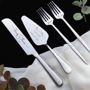May include: A set of stainless steel wedding cake serving utensils including a knife, a cake server, and two forks. The knife is engraved with Terry & Bria 10.18.2025, the server with Mr & Mrs Smith October 18 2025, and the forks with Bria, Jerry, and 10.18.2025.