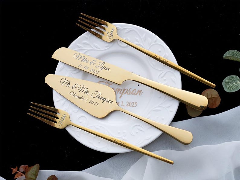 May include: A set of gold-toned stainless steel cutlery including two forks, a knife, and a cake server. The items are engraved with the names Mike and Lynn, the date 11.01.2025, and the text Mr. & Mrs. Thompson, November 1, 2025.