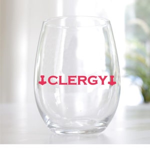 May include: A clear stemless wine glass with the word "CLERGY" in red, centered on the glass. The word has a downward-pointing arrow above and below it. The glass is on a white surface.