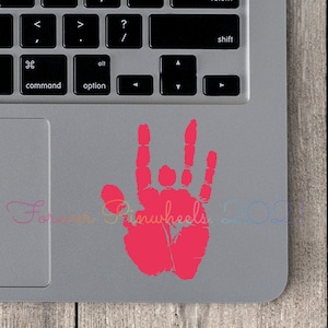May include: A hot pink handprint sticker on a gray laptop. The handprint is in the shape of the "I love you" sign in American Sign Language. The text "Forever Pinwheels 2021" is in the lower left corner.